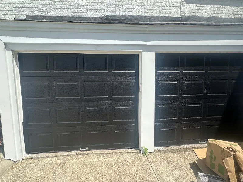 Black dual raised-panel garage doors on gray stone-faced home